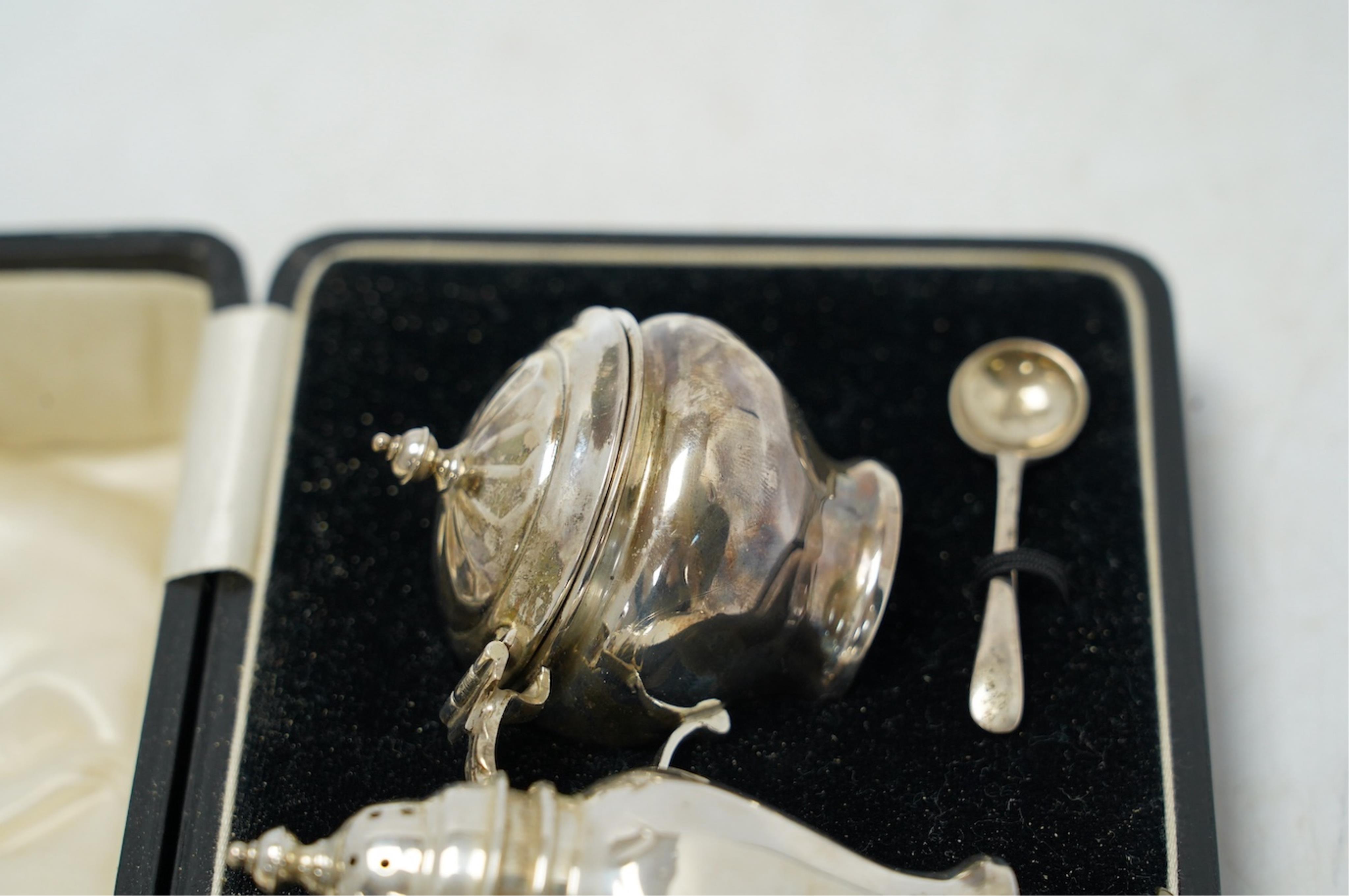 A cased George V silver three piece condiment set, Z. Barraclough & Sons, Chester, 1931, with two associated silver spoons. Condition - fair